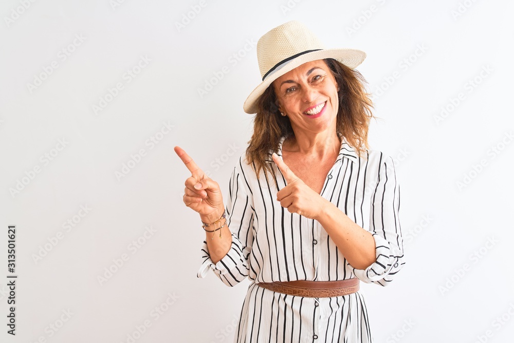 Middle age businesswoman wearing striped dress and hat over isolated white background smiling and looking at the camera pointing with two hands and fingers to the side. Middle age businesswoman wearing striped dress and hat over isolated white background smiling and looking at the camera pointing with two hands and fingers to the side.