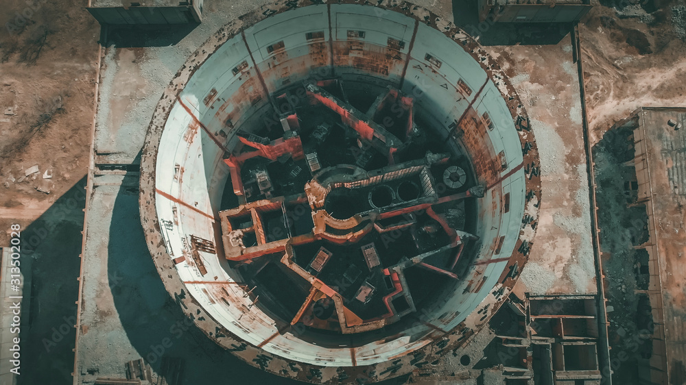 Fototapeta premium Aerial top view of abandoned and ruined Nuclear Power Plant. Large industrial construction with round tower of atomic reactor, post-apocalypse and world war concept, drone shot.