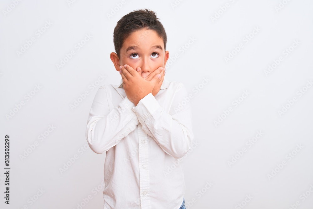Beautiful kid boy wearing elegant shirt standing over isolated white background shocked covering mouth with hands for mistake. Secret concept. Beautiful kid boy wearing elegant shirt standing over isolated white background shocked covering mouth with hands for mistake. Secret concept.