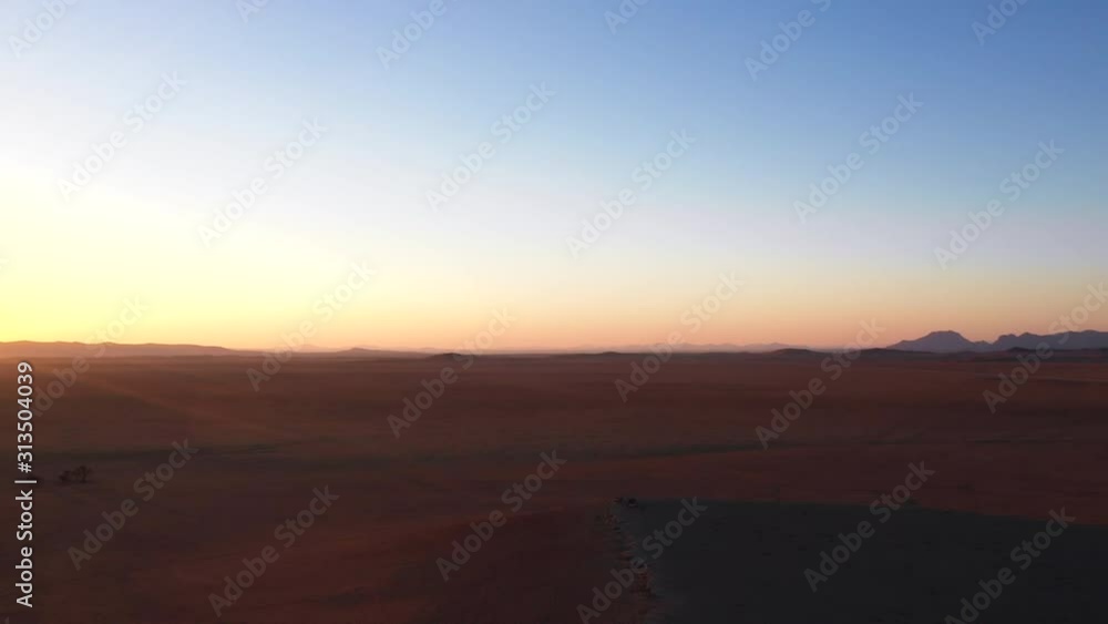 Aerial shot of sunset over Namibian desert and truck in distant Aerial shot of sunset over Namibian desert and truck in distant