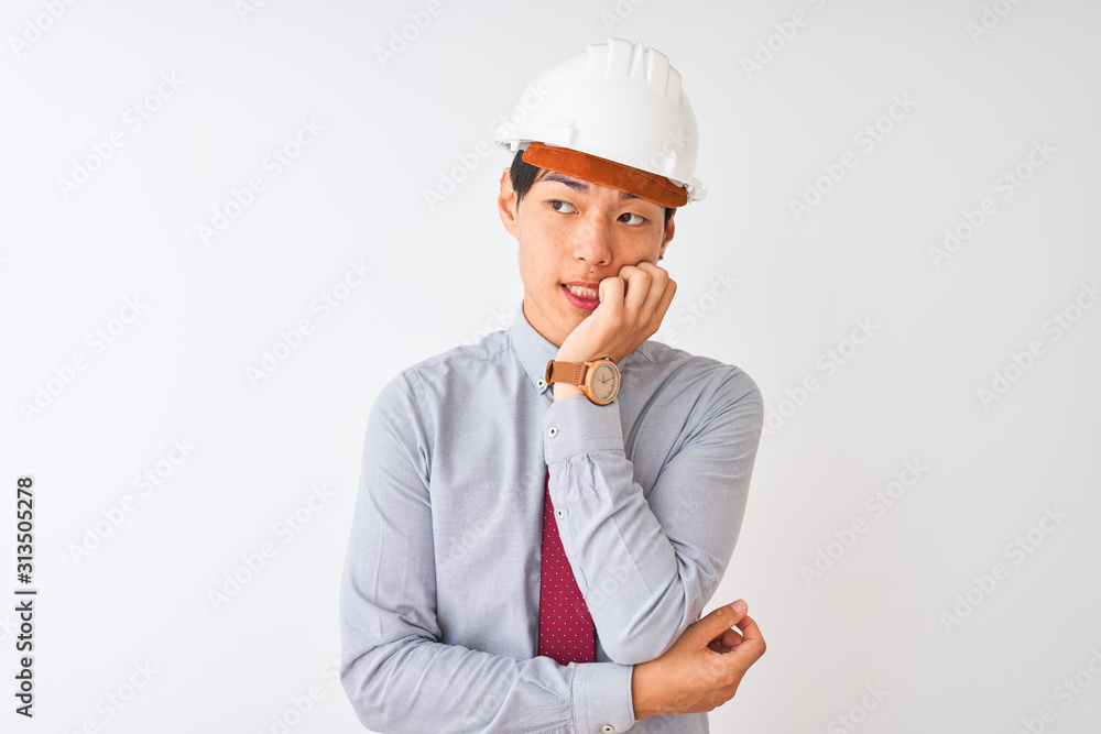 Chinese architect man wearing tie and helmet standing over isolated white background looking stressed and nervous with hands on mouth biting nails. Anxiety problem. Chinese architect man wearing tie and helmet standing over isolated white background looking stressed and nervous with hands on mouth biting nails. Anxiety problem.