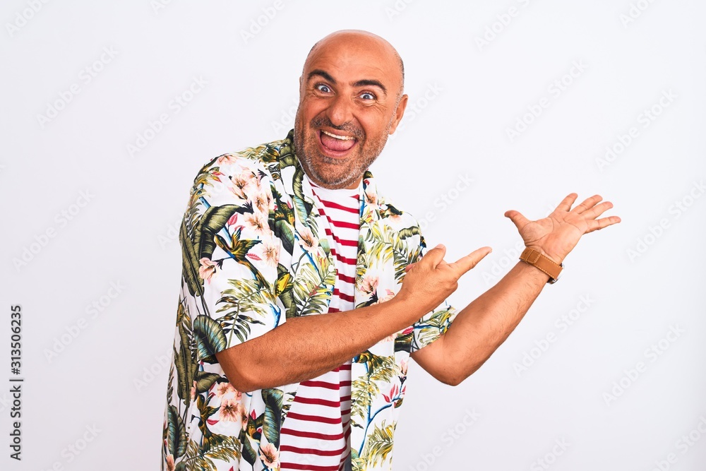 Fototapeta premium Middle age handsome man on holiday wearing summer shirt over isolated white background amazed and smiling to the camera while presenting with hand and pointing with finger.