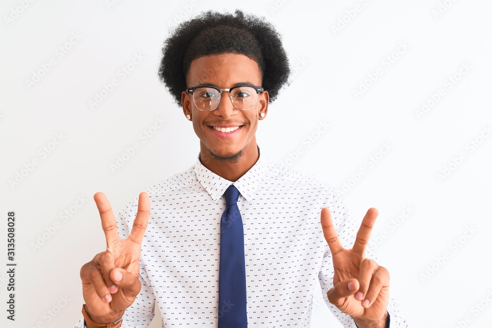 Young african american businessman wearing tie and glasses over isolated white background smiling looking to the camera showing fingers doing victory sign. Number two. Young african american businessman wearing tie and glasses over isolated white background smiling looking to the camera showing fingers doing victory sign. Number two.