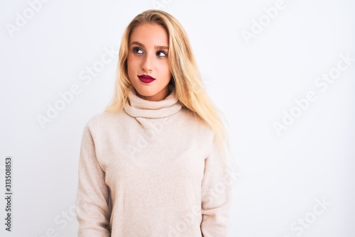Young beautiful woman wearing turtleneck sweater standing over isolated white background smiling looking to the side and staring away thinking.