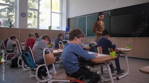 Wallpaper Mural Asian female teacher near desk of mixed race schoolboy with failed drawing and asking about difficulties. Skillful teacher controlling creative process during drawing lesson in junior school Torontodigital.ca