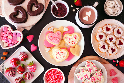 Valentines Day table scene with assorted sweets and cookies. Above view over a dark background. Love and hearts theme.