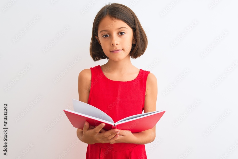 Beautiful student child girl reading red book standing over isolated white background with a confident expression on smart face thinking serious Beautiful student child girl reading red book standing over isolated white background with a confident expression on smart face thinking serious
