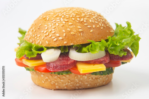 Hamburger with vegetables and sausage on a white background. Fast food and breakfast. Calories and diet.