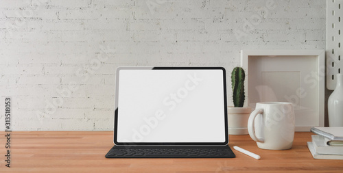 Cropped shot of comfortable workplace with mock-up and tablet office supplies on wooden table and brick wall