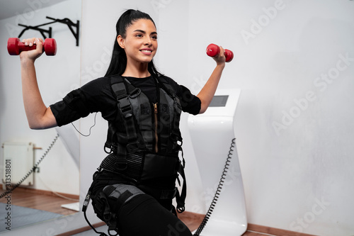 Woman working out with dumbbells in ems suit  photo