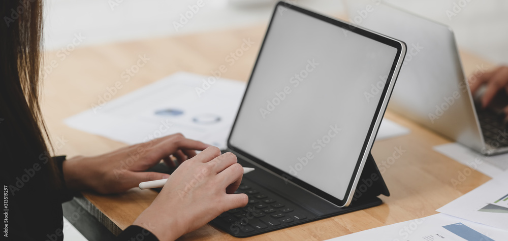 Close-up view of young businesswoman planing her strategy while using blank screen tablet - obrazy, fototapety, plakaty 
