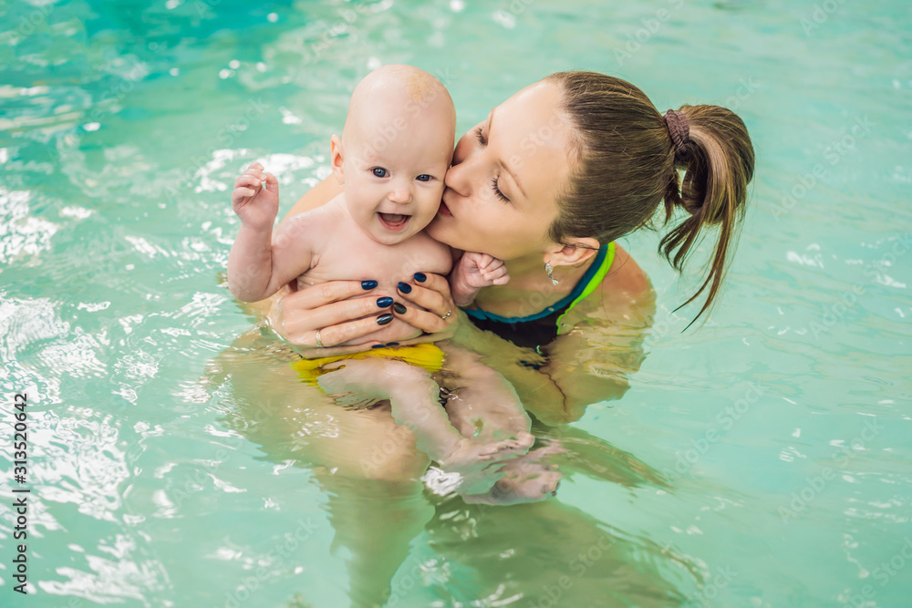 Beautiful mother teaching cute baby girl how to swim in a swimming pool. Child having fun in water with mom Beautiful mother teaching cute baby girl how to swim in a swimming pool. Child having fun in water with mom