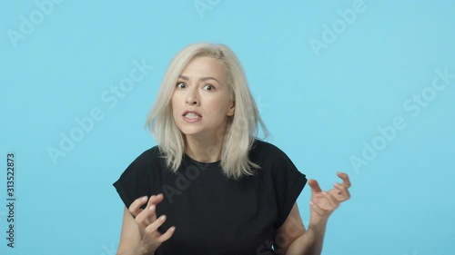 Swear god gonna kill you. Slow-motion aggressive, pissed-off mad blond woman losing temper, clenching hands want strangle someone, squeeze teeth and grimacing angry, standing blue background