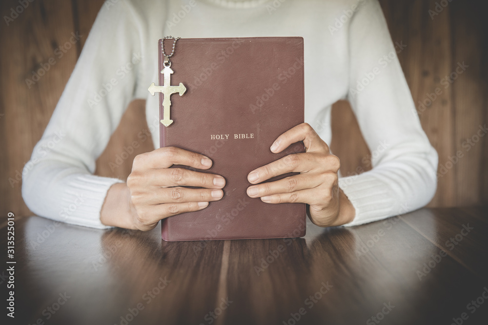 Bible and crucifix. A young woman asks blessings from God with the power and power of holiness, which brings luck and shows forgiveness with the power of religion, faith, worship, Christian thought.