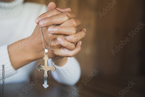Картината върху платно A close-up shot of a woman with a cross and praying Pray or pray to God Concepts of religion, beliefs and people Begging for forgiveness and believing in goodness