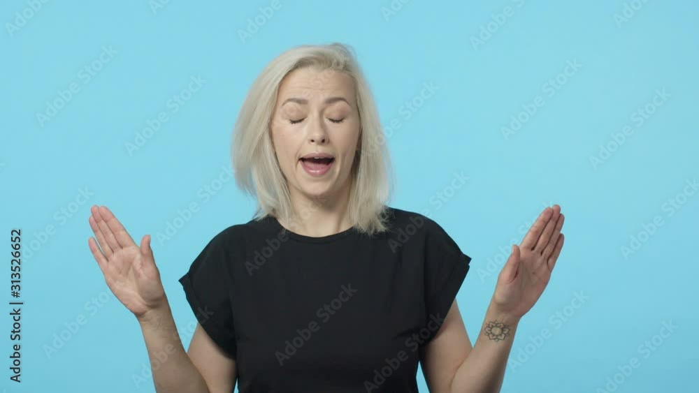 Slow-motion adult blond woman feeling skeptical and displeased bad idea, shake head and hands, showing stop, refusal gesture, say no, deny and reject awful offer, standing reluctant blue background Slow-motion adult blond woman feeling skeptical and displeased bad idea, shake head and hands, showing stop, refusal gesture, say no, deny and reject awful offer, standing reluctant blue background