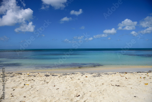 Tropical sandy beach, blue Caribbean sea, sky and clouds