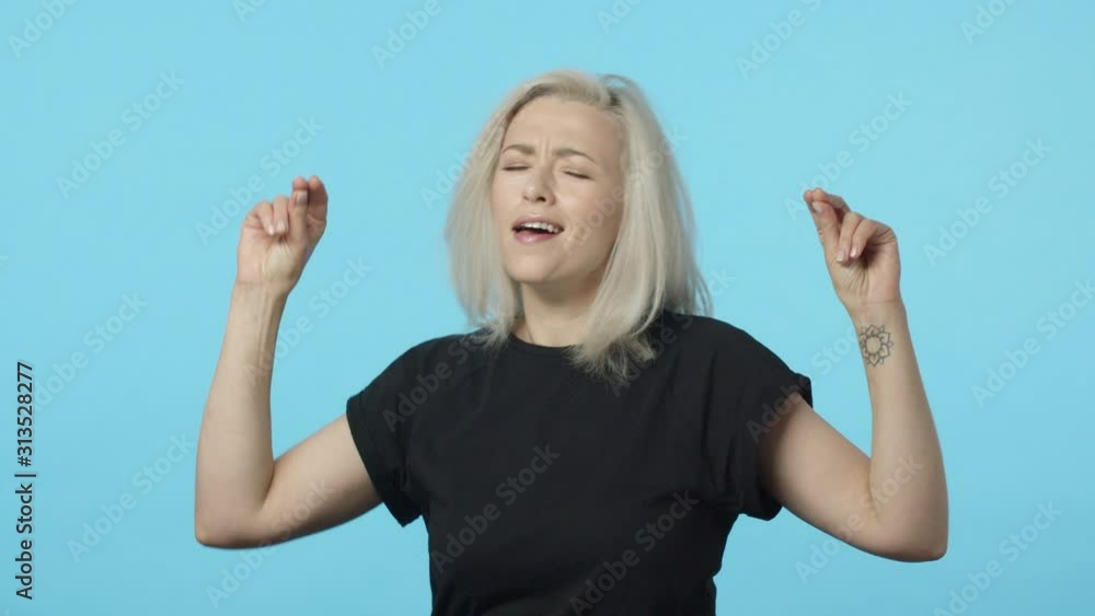 Rock-n-roll baby. Slow-motion attractive mother going wild and carefree, attend awesome party, cool concert, dancing joyfully, triumphing, making champion dance, smiling satisfied, blue background