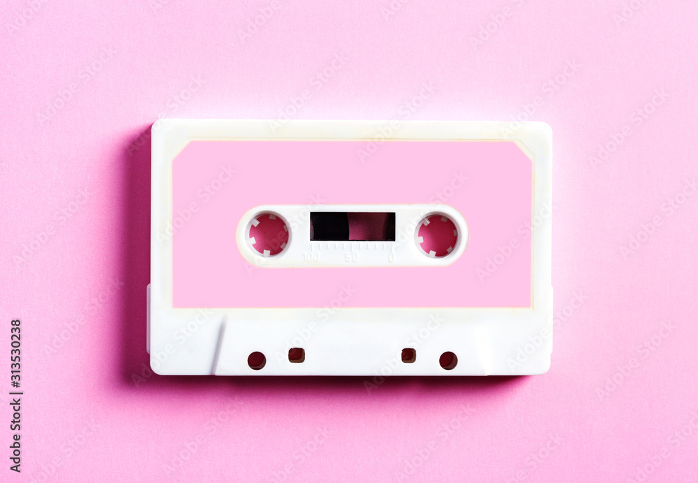 Pink retro cassette tape on pink background, top view.