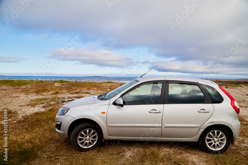 Fototapeta Naklejka Na Ścianę i Meble -  Car on the beach of sea, river or lake with rocks on a cloudy day. The fjord of Northern Norway