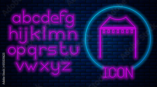 Glowing neon Camping tent icon isolated on brick wall background. Carnival camping tent. Amusement park. Neon light alphabet. Vector Illustration