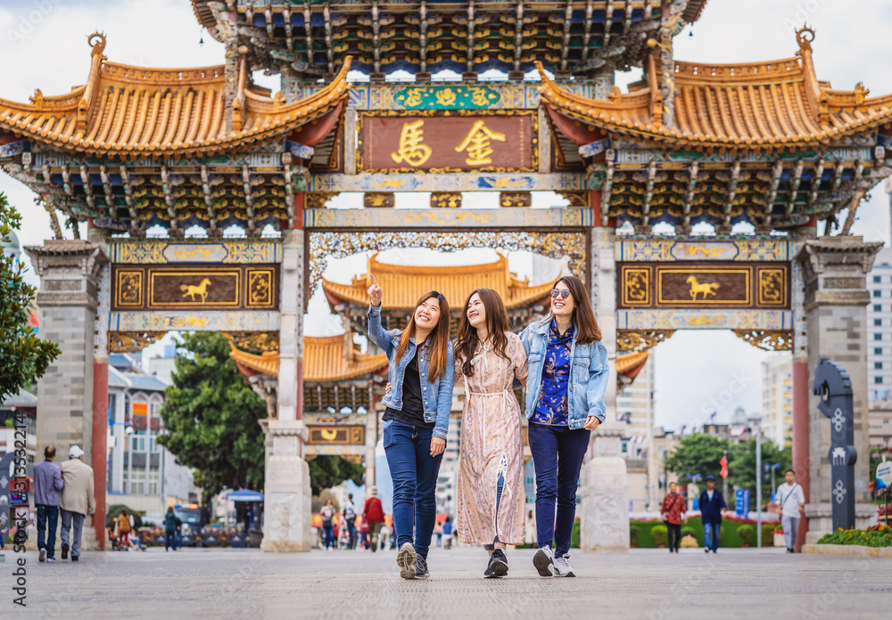Portrait Three asian happiness women walking and sightseeing together when travelling over the Jinbi square, Kunming, China, travel and tourism with friendship concept,Chinese Text is Golden Horse