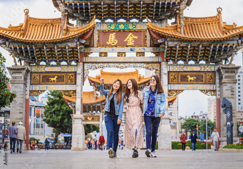 Portrait Three asian happiness women walking and sightseeing together when travelling over the Jinbi square, Kunming, China, travel and tourism with friendship concept,Chinese Text is Golden Horse photo