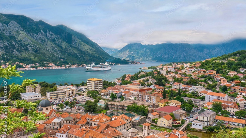 The picturesque town of Kotor, Montenegro, and its long bay and surrounding mountains, as a cruise ship enters the sheltered harbor.