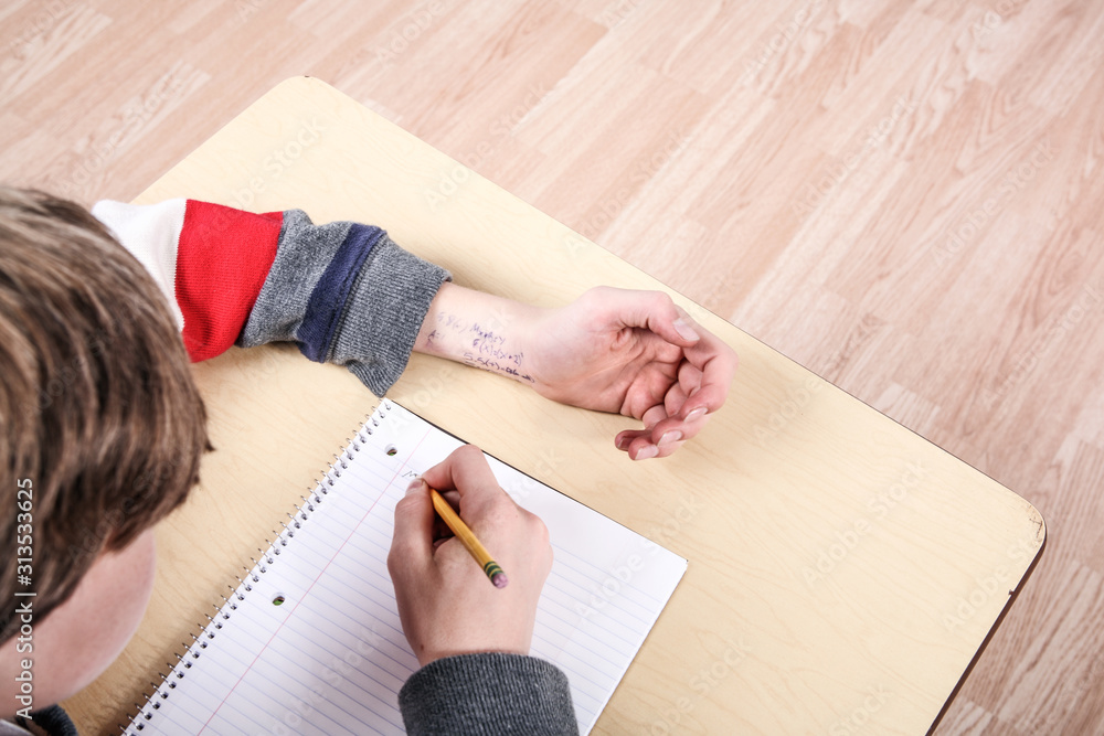 Student cheating on test with answers written on his arm Student cheating on test with answers written on his arm