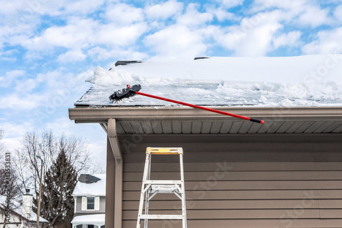 Gutters with ice dam and broom for raking snow off of roof photo