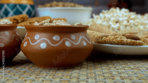 Closeup shot of edible items consumed during the Lohri and wintertime in India. Pan shot of various Lohri items like  til patti  rewri  popcorns  peanuts chikki  gajak rolls  etc placed on the dini... photo