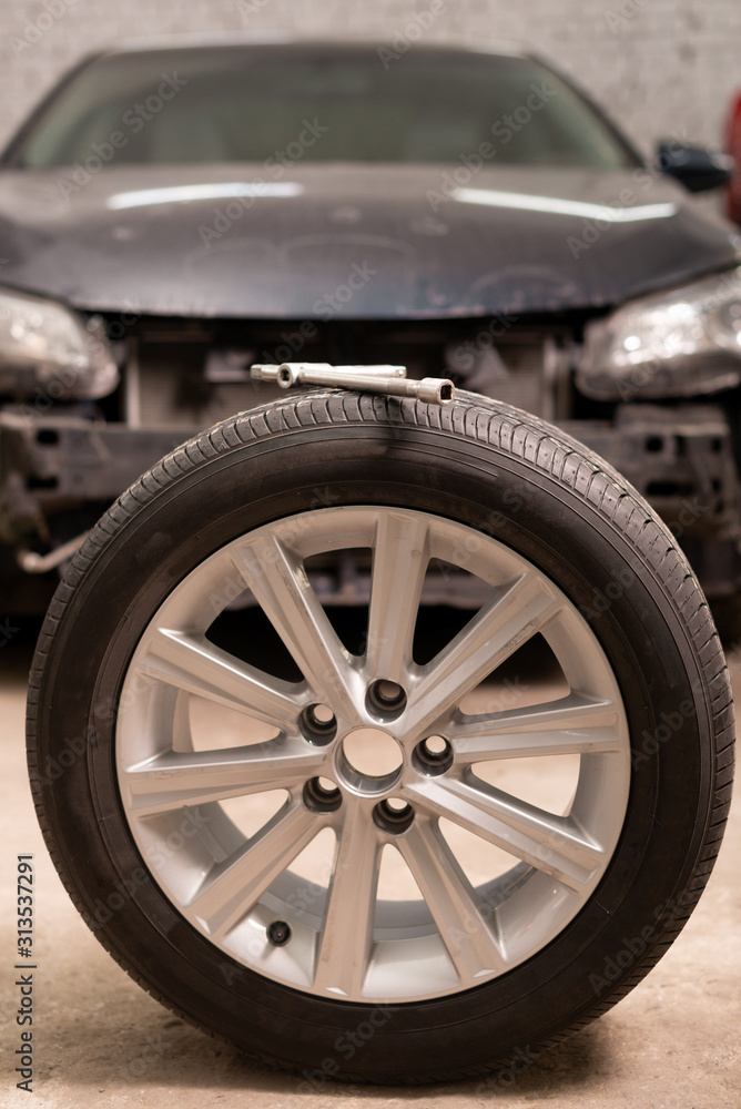 Close-up of new wheel to replace on old car in garage. Close up Close-up of new wheel to replace on old car in garage. Close up