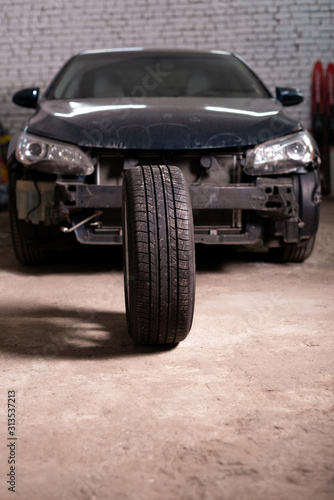 Photo of a car tire tire on the background of a passenger car without a bumper © mtrlin