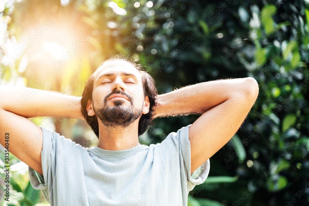 A bearded man is meditating outdoor in the park with face raised up to sky and eyes closed on sunny summer day. Concept of meditation, dreaming, wellbeing healthy lifestyle A bearded man is meditating outdoor in the park with face raised up to sky and eyes closed on sunny summer day. Concept of meditation, dreaming, wellbeing healthy lifestyle