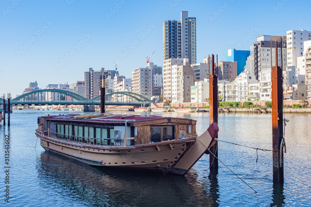 Japan. Tokyo. Rivers Of Tokyo. The ship is moored near the shore. River bridge. Ship on the background of a residential district of Tokyo. Construction of houses in the capital of Japan.