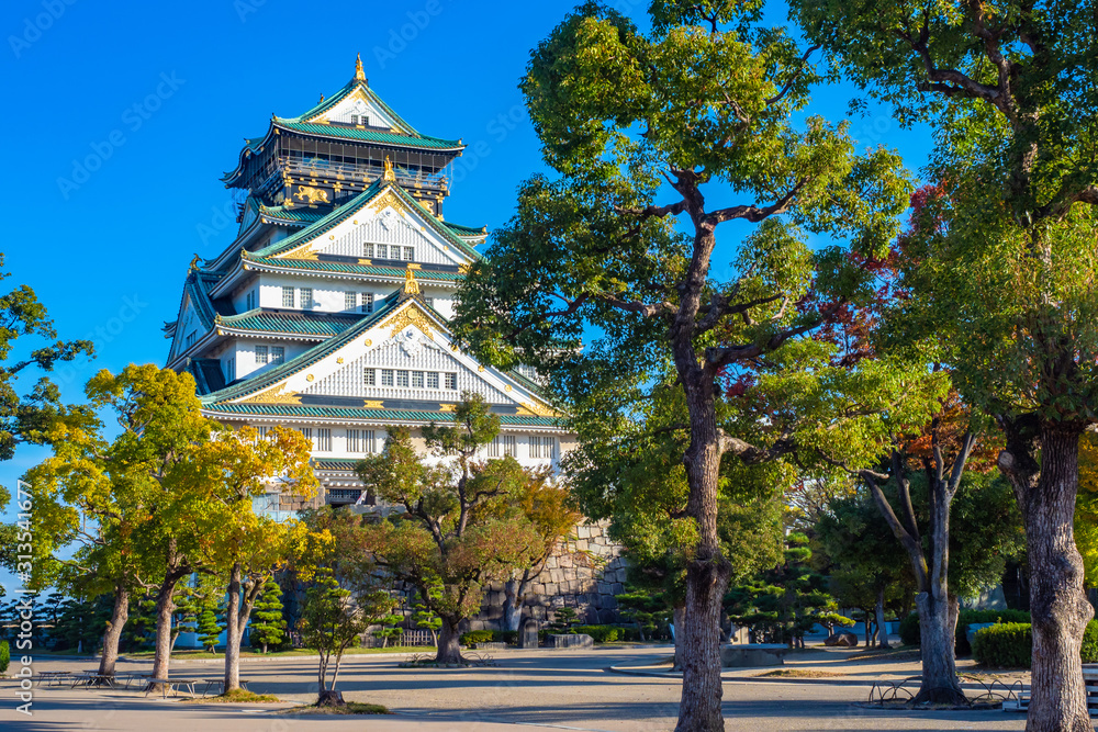 Japan. Osaka. the Osaka castle. Japanese samurai castle. Osaka business card. Guide to Japan. Travel to East Asia. Castles Of Japan. Building on the background of trees. Japan. Osaka. the Osaka castle. Japanese samurai castle. Osaka business card. Guide to Japan. Travel to East Asia. Castles Of Japan. Building on the background of trees.