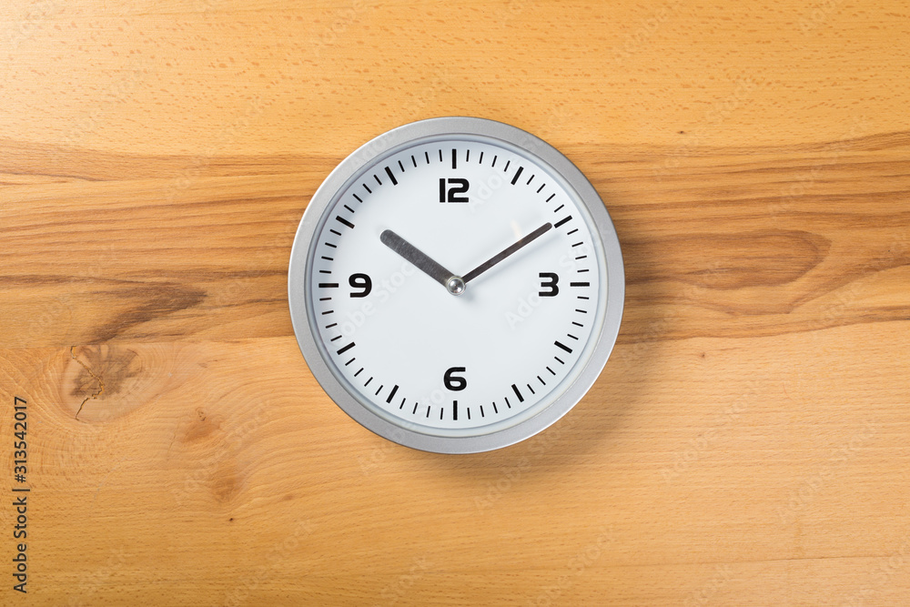 White wall clock with a yellow used hanging on the wall. Minimalist image of a wall clock on a wooden background with copy space White wall clock with a yellow used hanging on the wall. Minimalist image of a wall clock on a wooden background with copy space