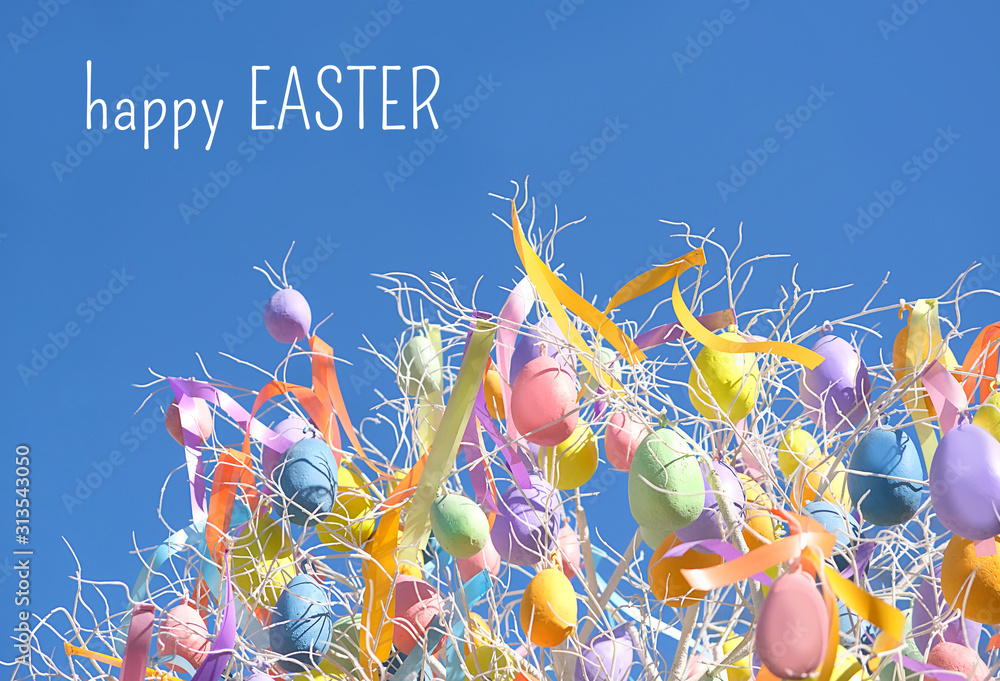 Obraz Szczęśliwy Wielkanocny wakacyjny pojęcia tło. Wielkanocni jajka na gałąź przeciw niebieskiemu niebu. Wielkanocny wystrój ulic wiosny. Świąteczny pomysł, kreatywny wystrój w minimalistycznym stylu.