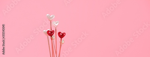 Metal pins for sewing with colored head in form of heart on pink background. Creative minimal Valentines Day Concept. banner, copy space