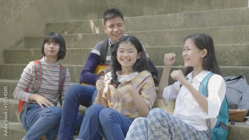 Group of asian teenager sitting in park and giving high five with friends,slow motion shot.