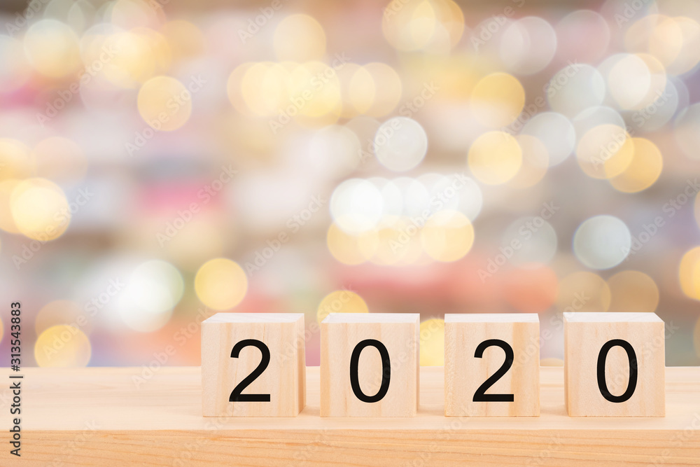 Happy new year 2020 text on wooden cubes on wooden pine table and blur light bokeh background. Banner with copy space for text. Happy new year 2020 text on wooden cubes on wooden pine table and blur light bokeh background. Banner with copy space for text.