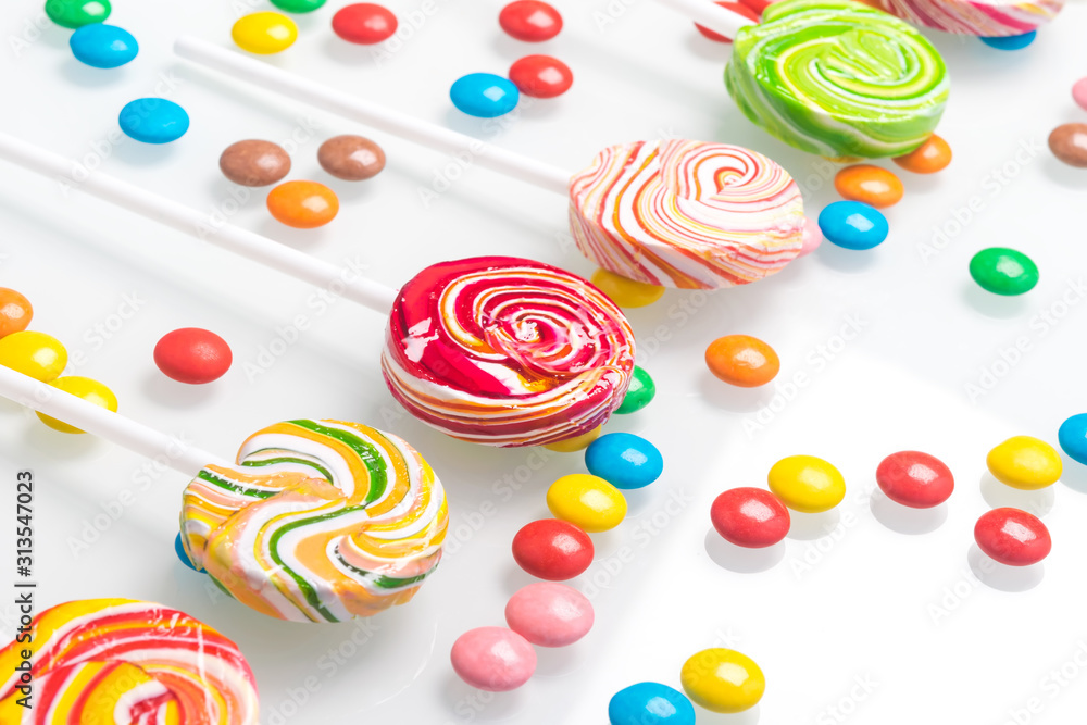 multi-colored chocolate dragees lie around a row of round lollipops