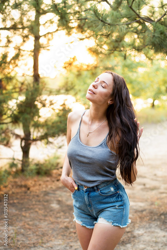 Portrait of pretty young woman standing near leaves outdoors