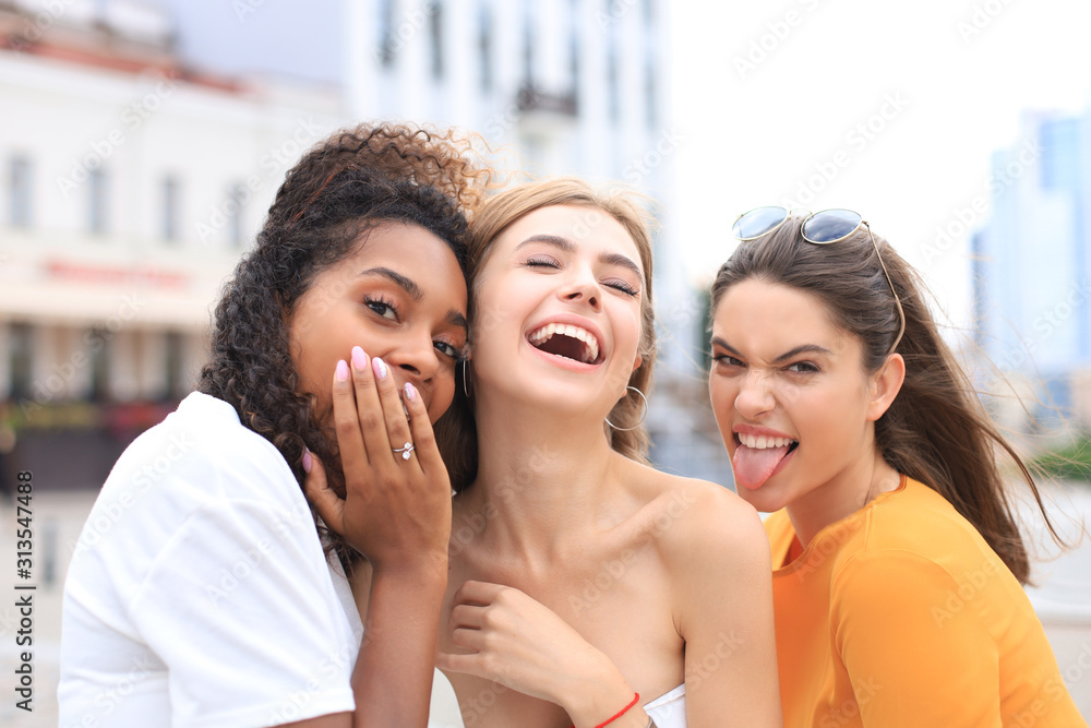 Three young smiling hipster women in summer clothes posing on street.Female showing positive face emotions. Three young smiling hipster women in summer clothes posing on street.Female showing positive face emotions.