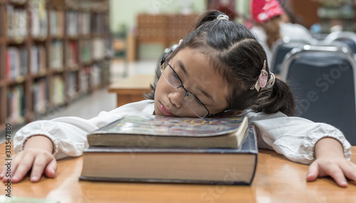 Obraz na plátne School student fall asleep while reading book in library or class from overwhelm