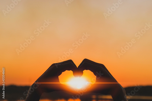 Silhouette love symbol heart symbol hand in the evening sunset.