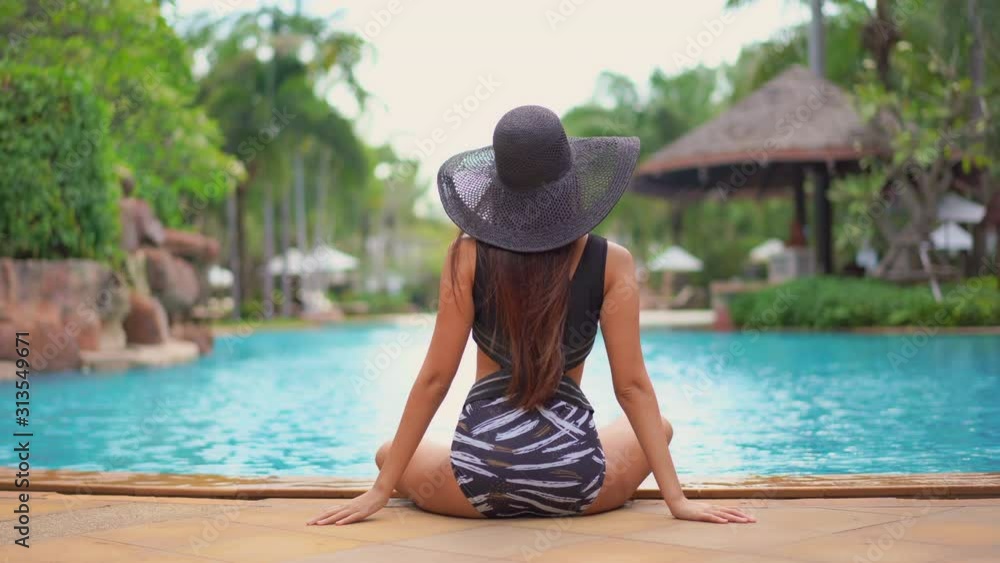 A young woman, with her back to the camera, in a bathing suit and ...