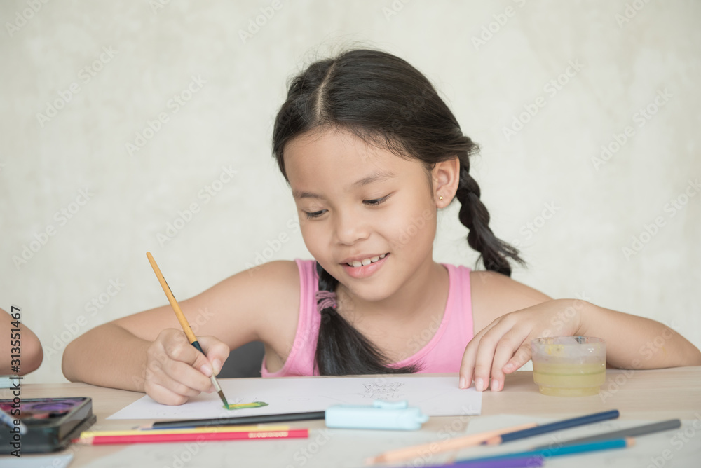 little girl with brush painting on table in School, education, cut girl painting in at her home. Selective focus and small depth of field, Painting with watercolor, drawing, Creativity concept. little girl with brush painting on table in School, education, cut girl painting in at her home. Selective focus and small depth of field, Painting with watercolor, drawing, Creativity concept.
