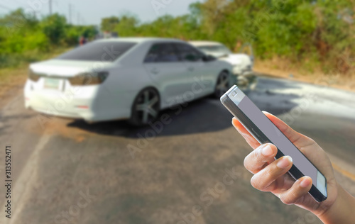person use mobile phone contact insurance ,blur image of car accident on the road as background,insurance concept.