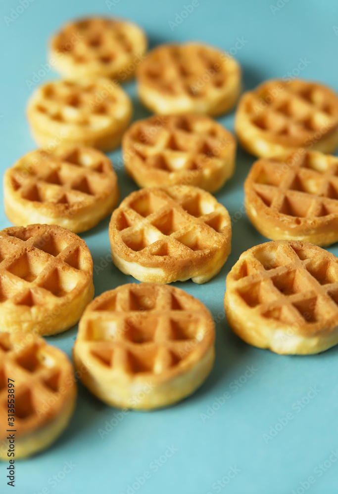Small round Belgian waffles on blue background. Close up food, top view